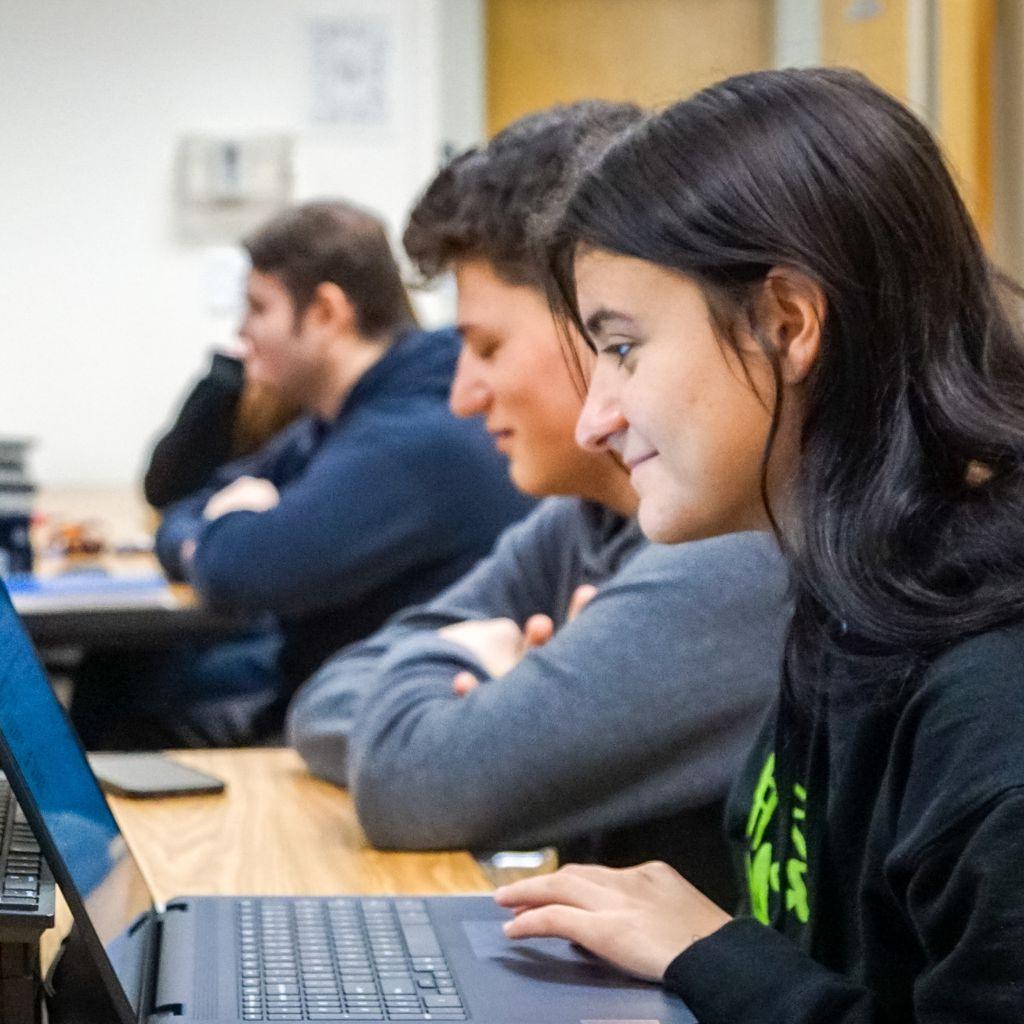 Students in class, focus on a female student on her laptop